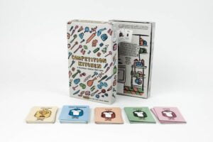 Board game "Competition Kitchen" displayed with its box and several card decks categorized as Challenge, Secret Ingredient, Flavor, Vegetable, and Protein on a white background.